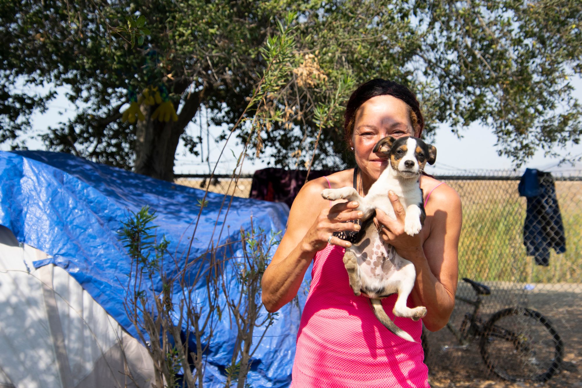 Tracy Harris, a resident of the homeless camp off Sacramento Street, holds up her dog.