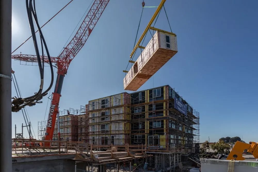 A crane stacks Factory_OS units for the Mayfair, a 156-unit building next to the El Cerrito Del Norte BART station.