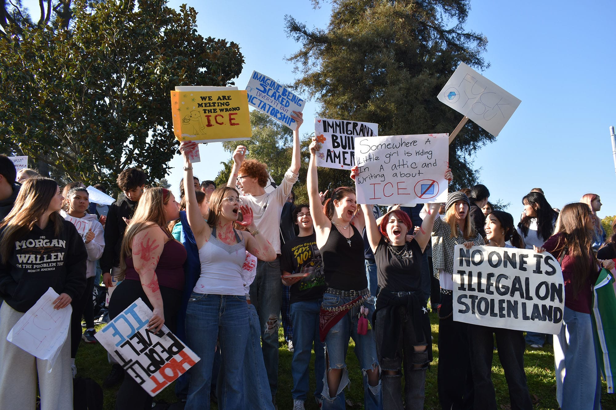 Students wave signs as cars honk in support. 